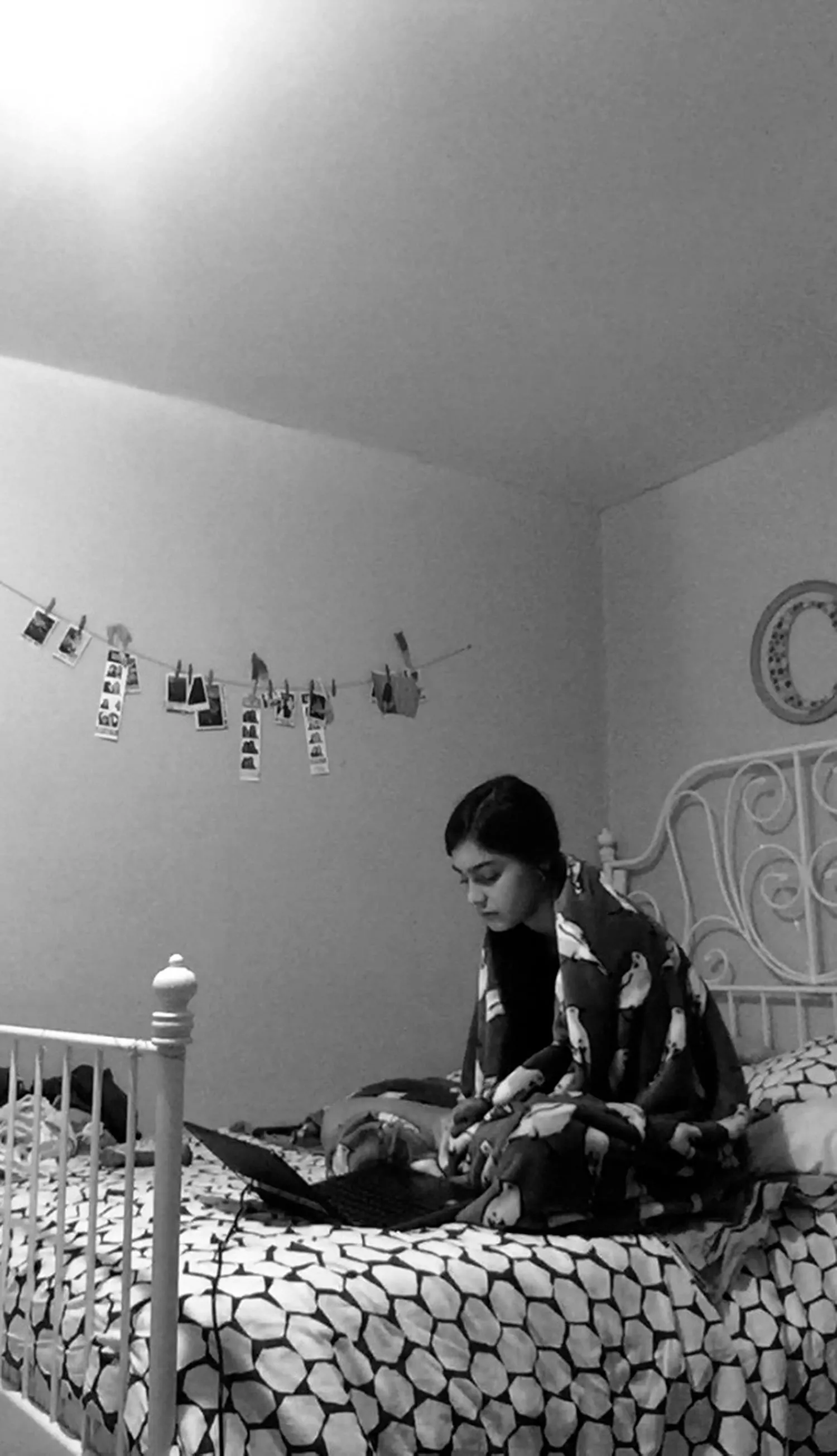 A girl on her laptop on her bed.