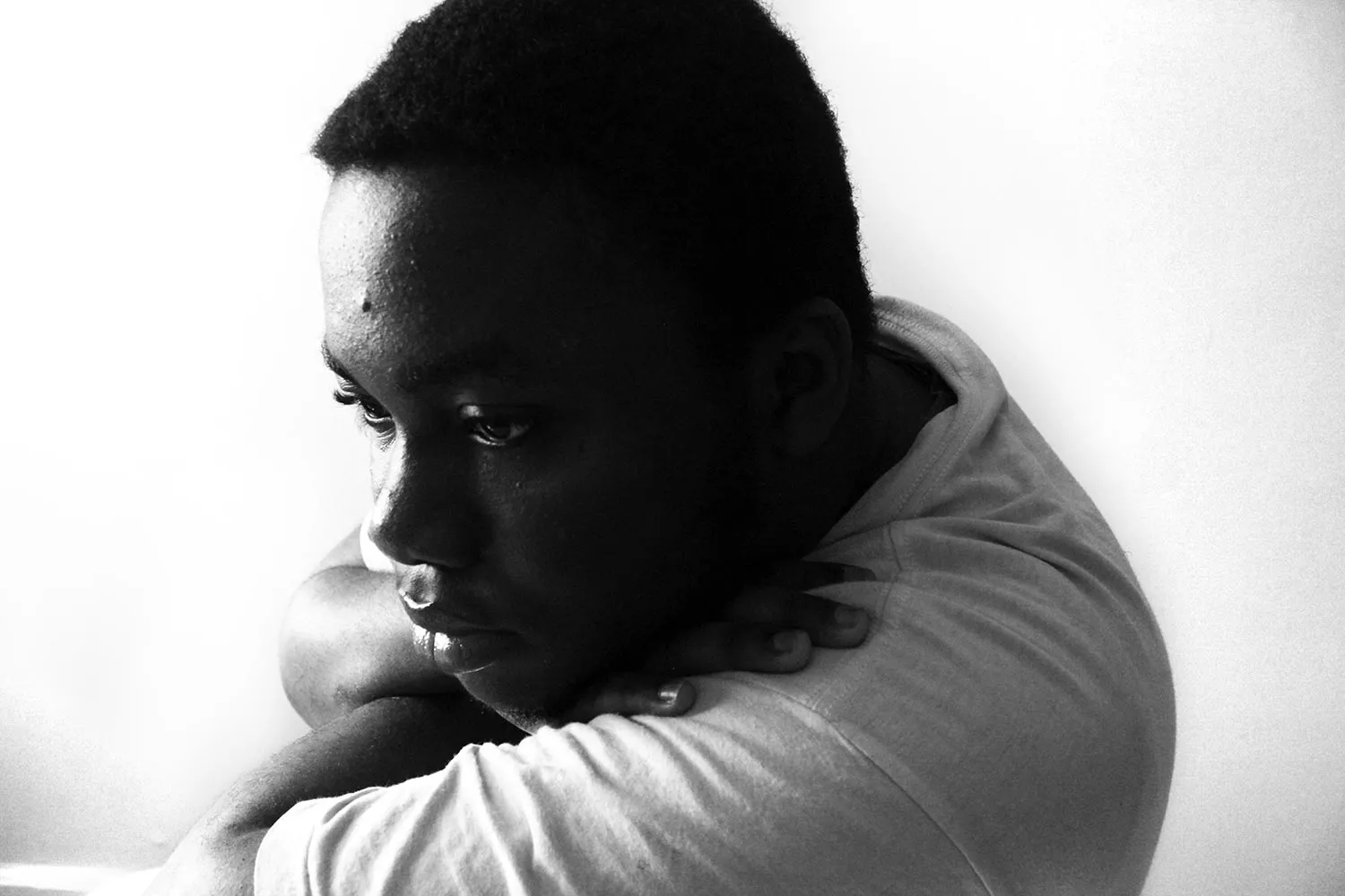 A Black man sitting with his arms folded under his chin