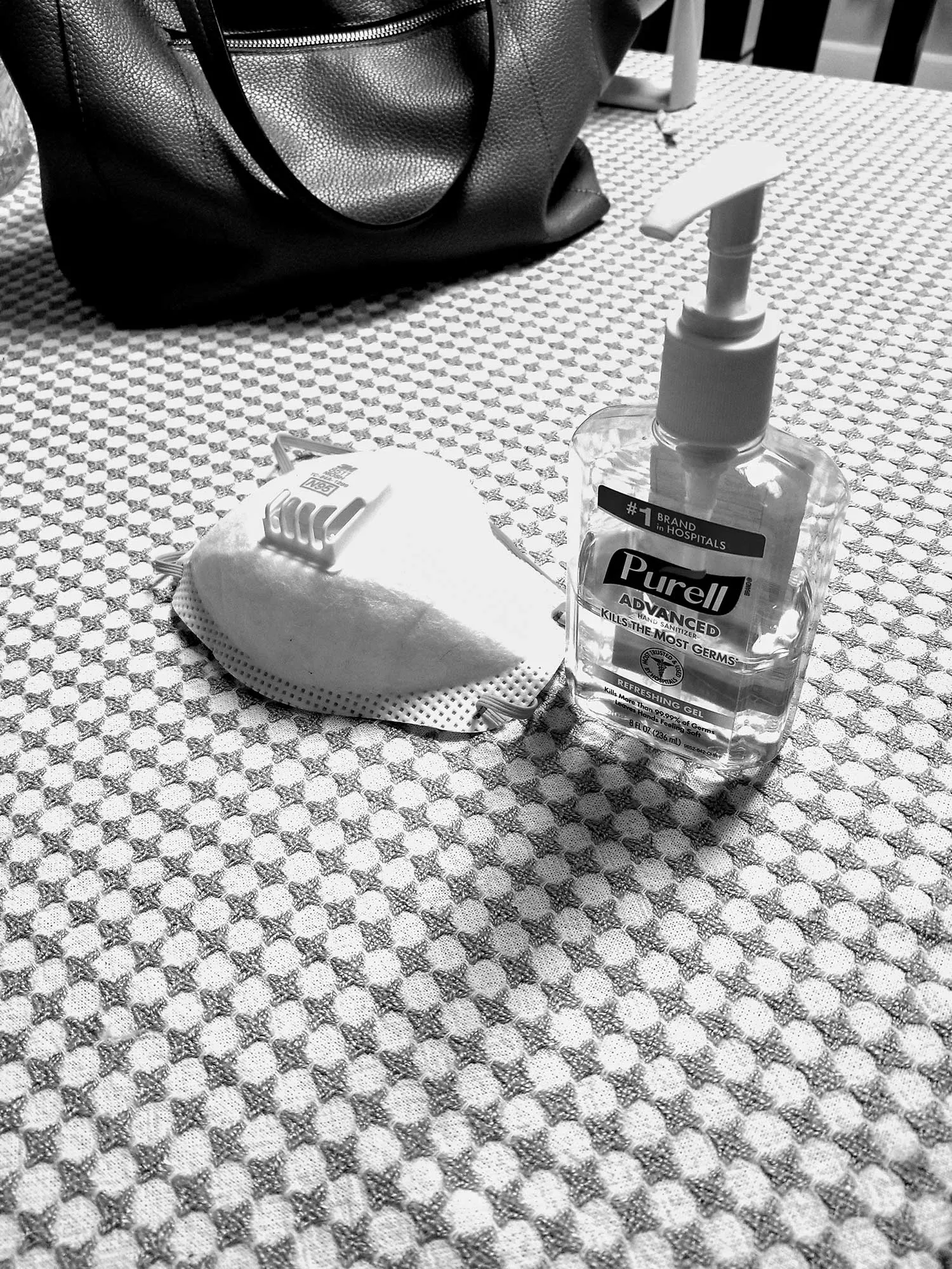 A table where a N95 mask and a bottle and hand sanitizer lay.