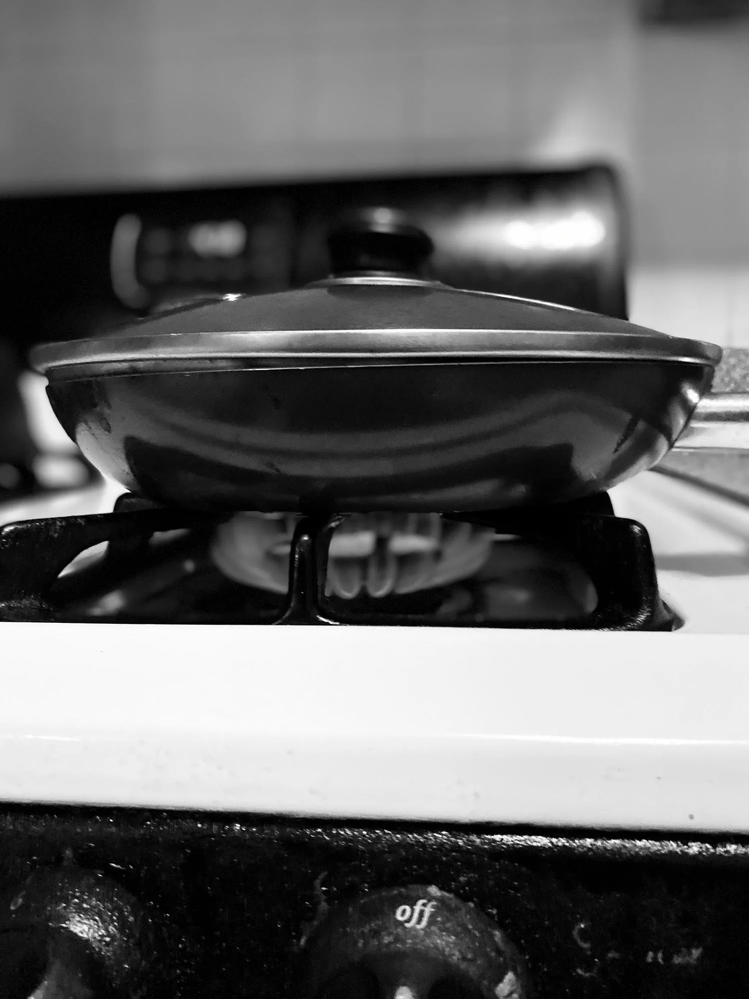 A lit stove and a saute pan with a top. 